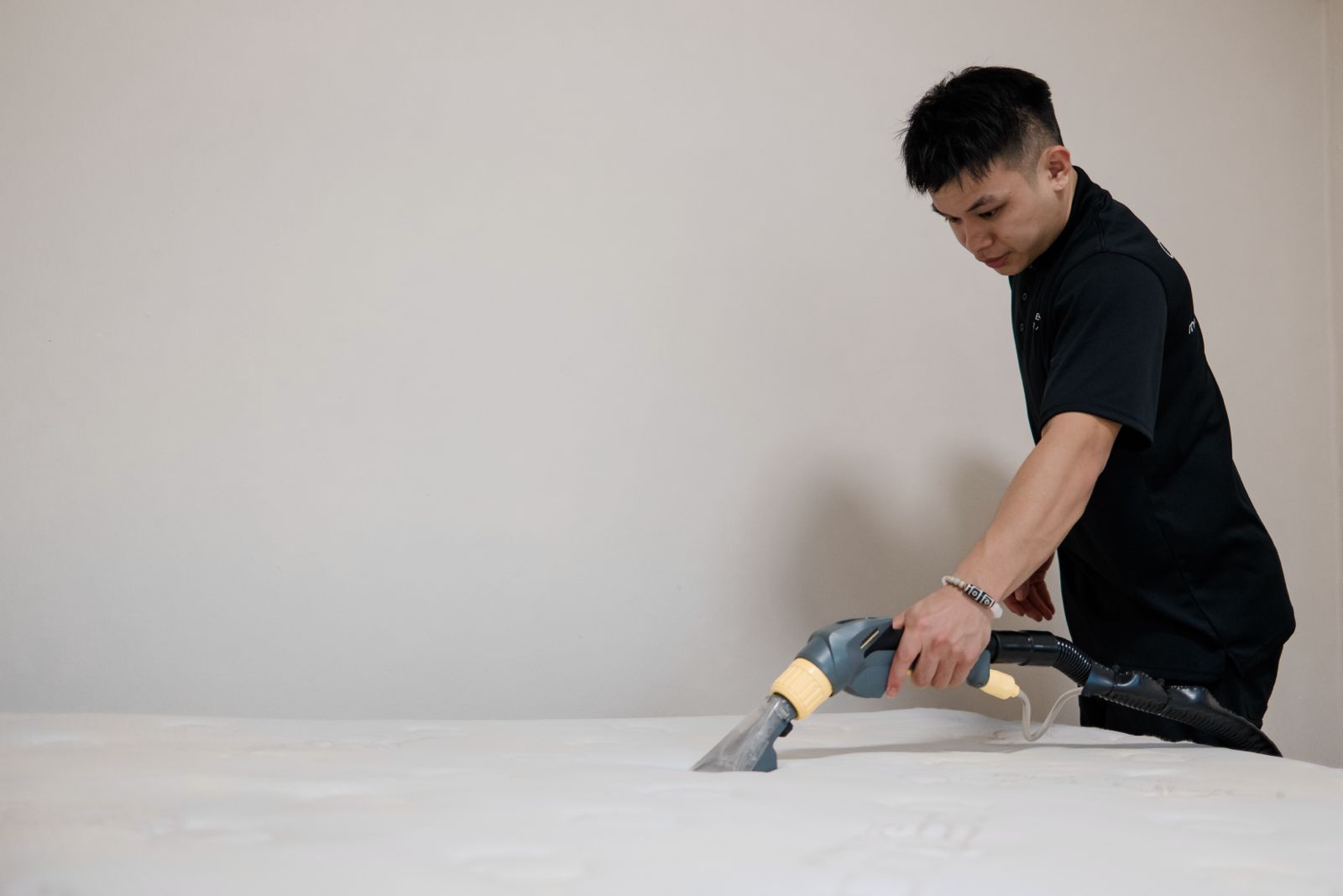 A Cleancraft technician vacuuming a white mattress with UV-C dry extraction in a Singapore home